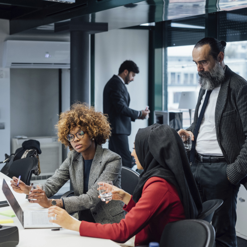 Multi cultural team members in an office looking at a laptop