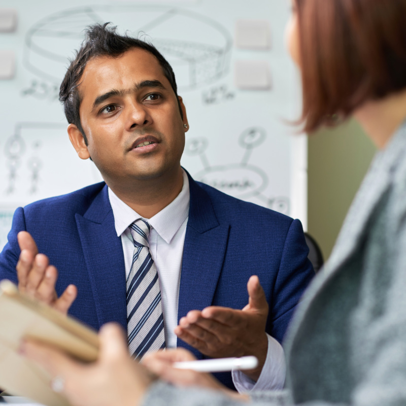 Confident middleaged businessman sitting at the table being coached to a woman