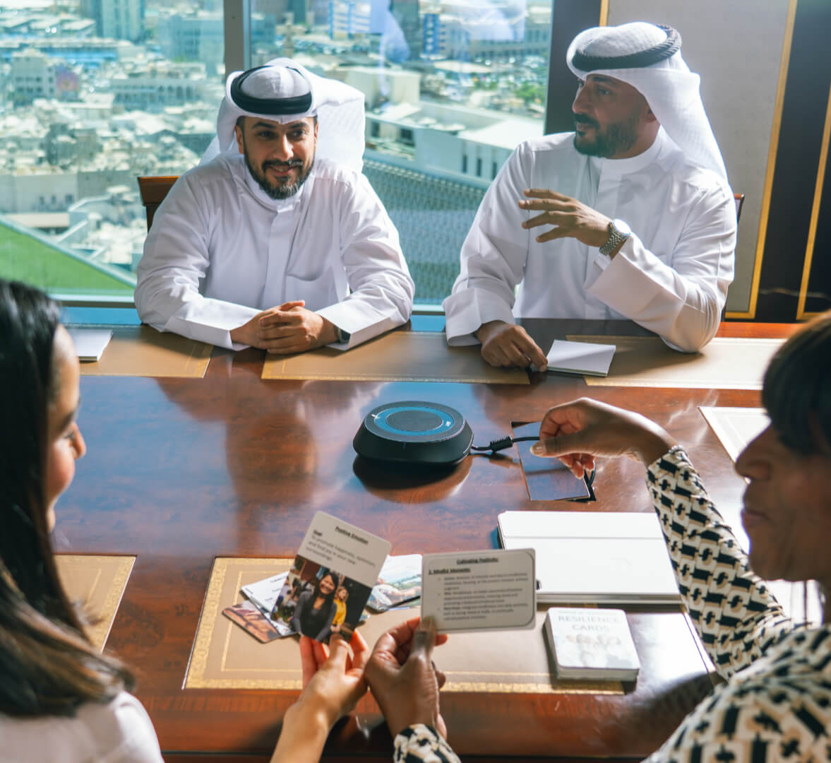 multi-cultural group sitting around a conference table holding and discussing resilience cards