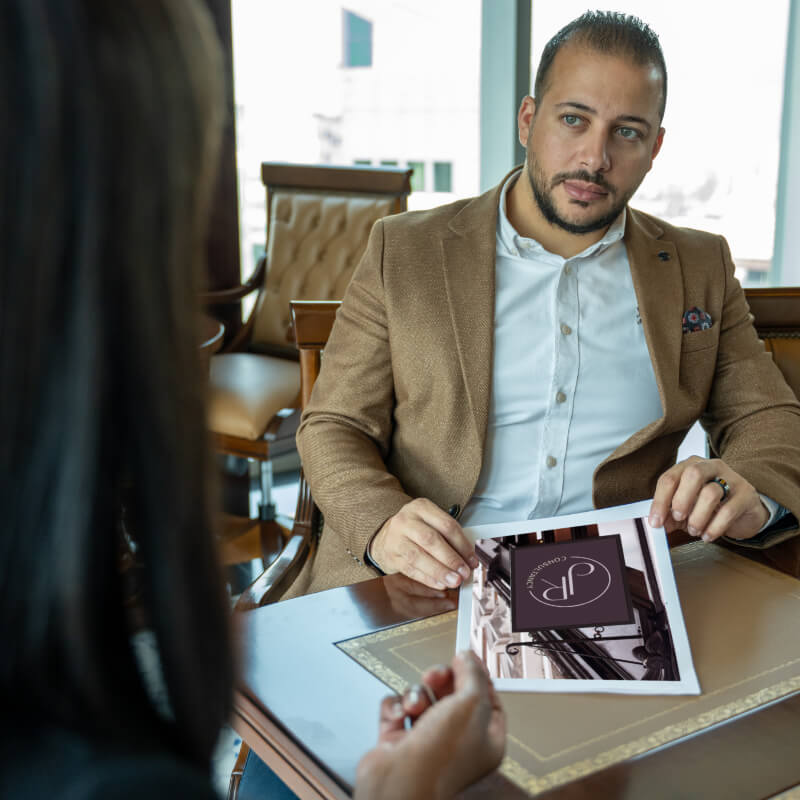 Handsome young executive in a one to one leadership coaching session holding a brochure and listening to a woman sitting opposite him