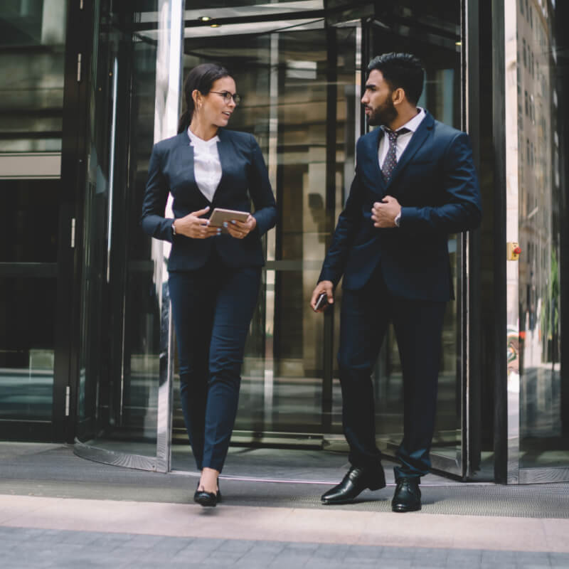 two executives leaving a corporate building in discussion