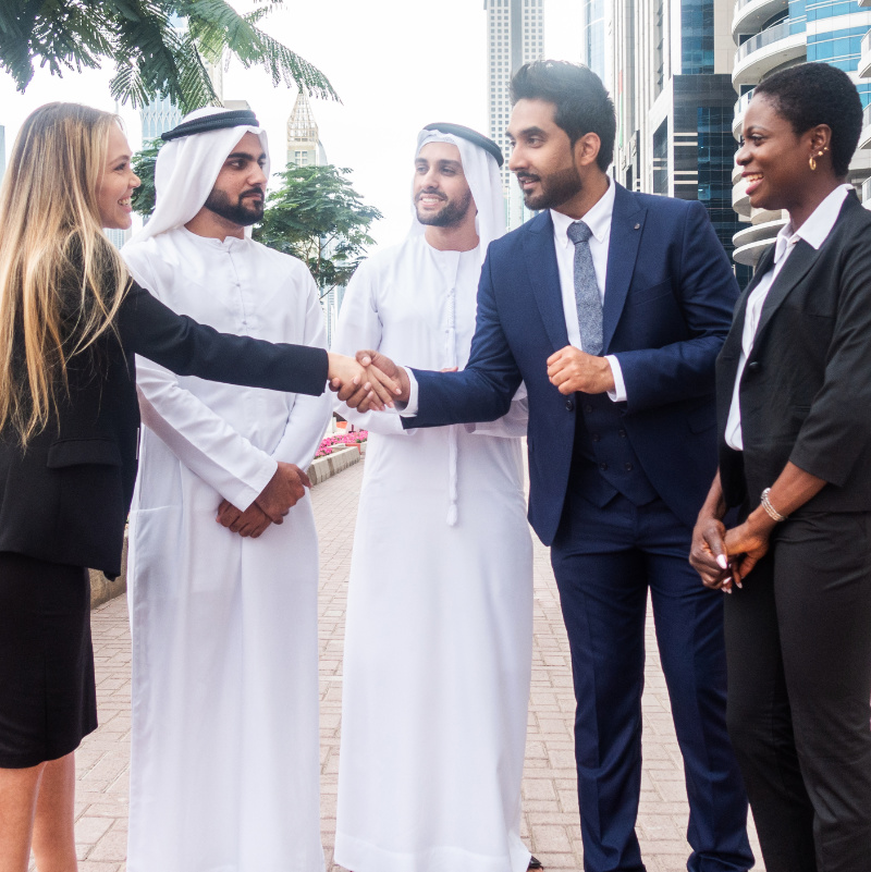 Multi-ethnic group of people on a business meeting in the UAE - Business men and women walking outdoors and talking about business, shaking hands