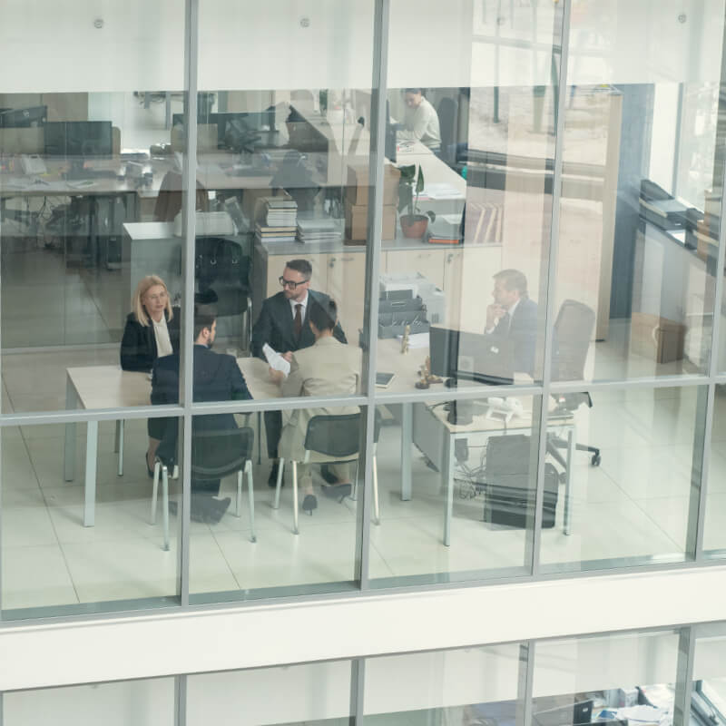 Above view of business people sitting at one table and working behind glass wall in office lobby