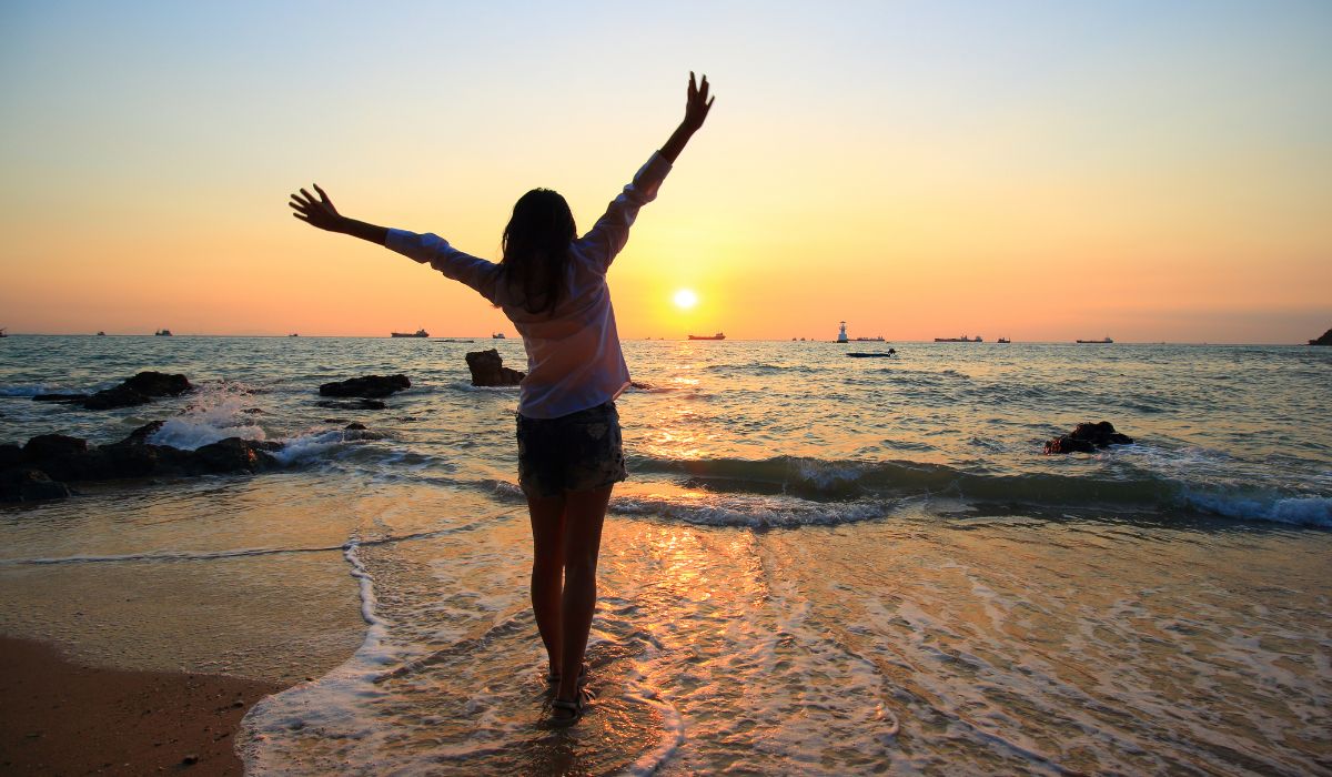 Women stretching on a beach admiring the sun set, enjoying some mindfullness